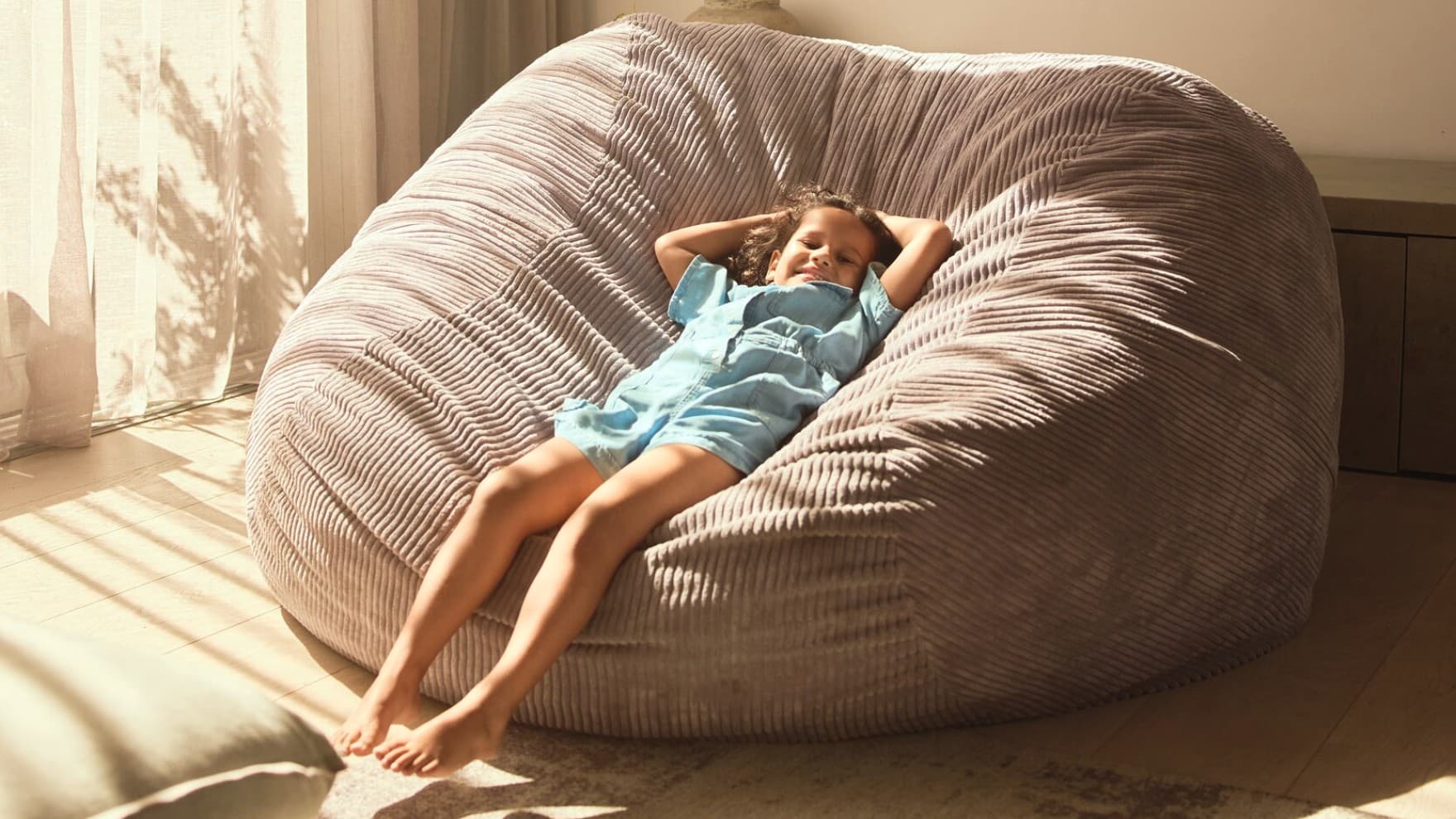 Copil care se relaxeaza pe un fotoliu puf