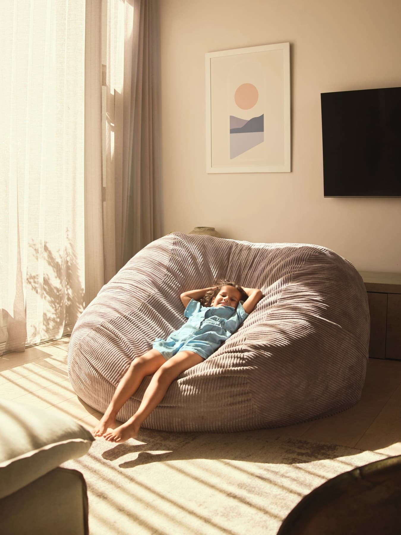 Copil care se relaxeaza pe un fotoliu puf