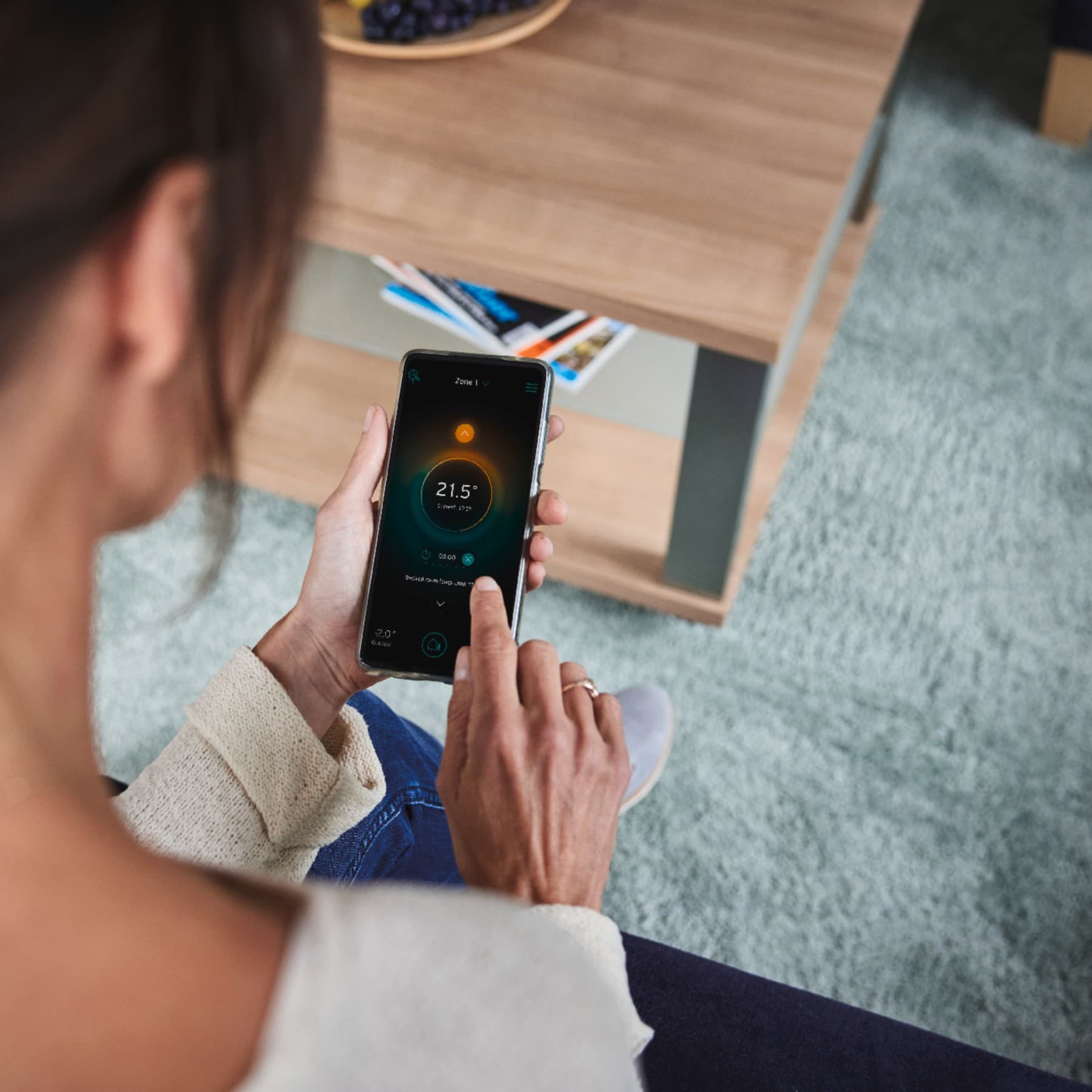 O femeie isi configureaza sistemul inteligent de pe telefon