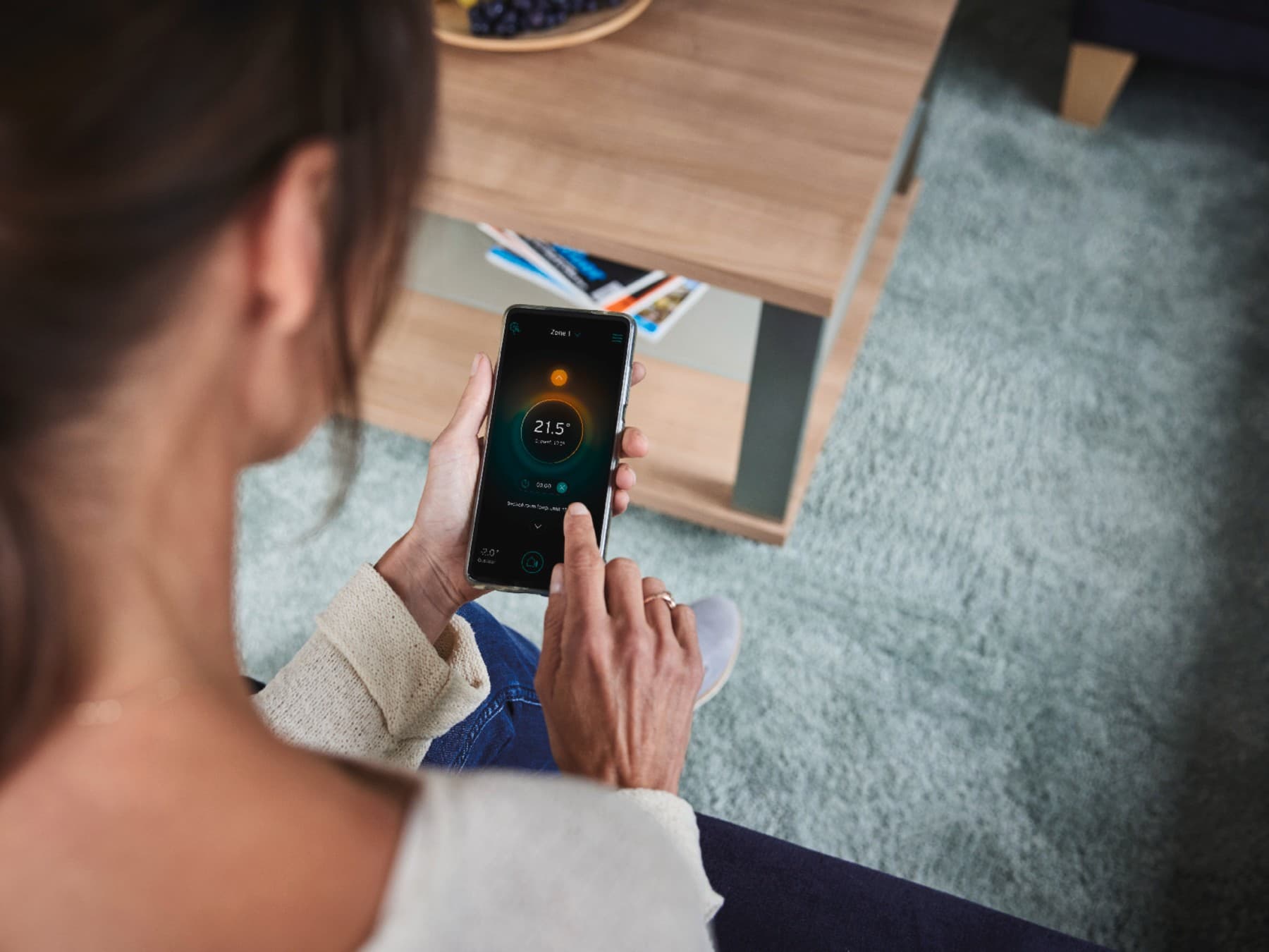 O femeie isi configureaza sistemul inteligent de pe telefon