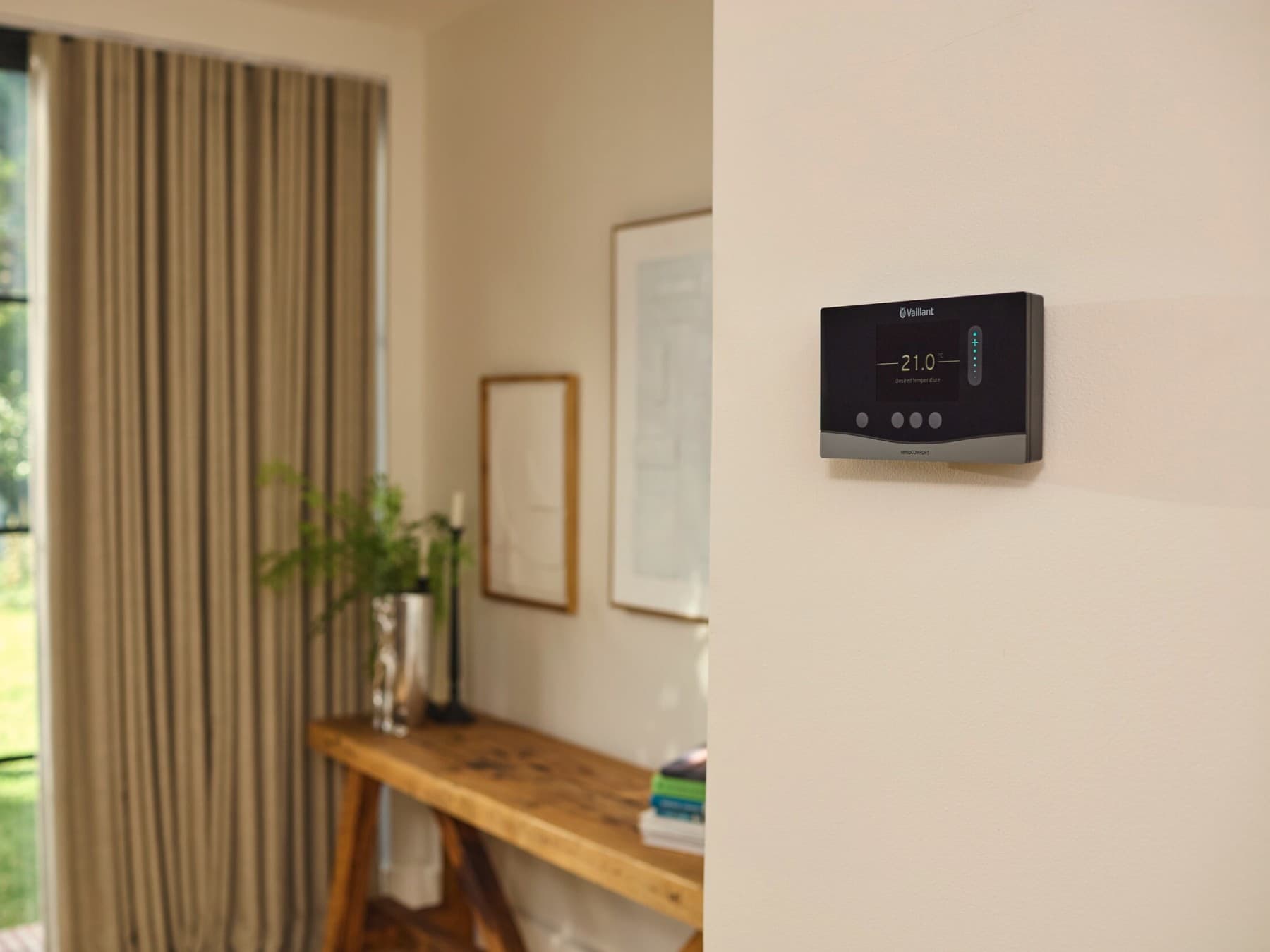 Un termostat modern Vaillant montat pe peretele unui living.