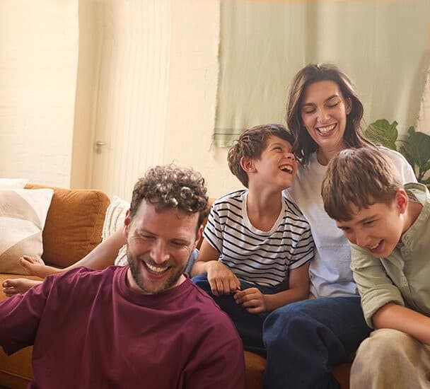 O familie asezata pe canapeaua din sufragerie