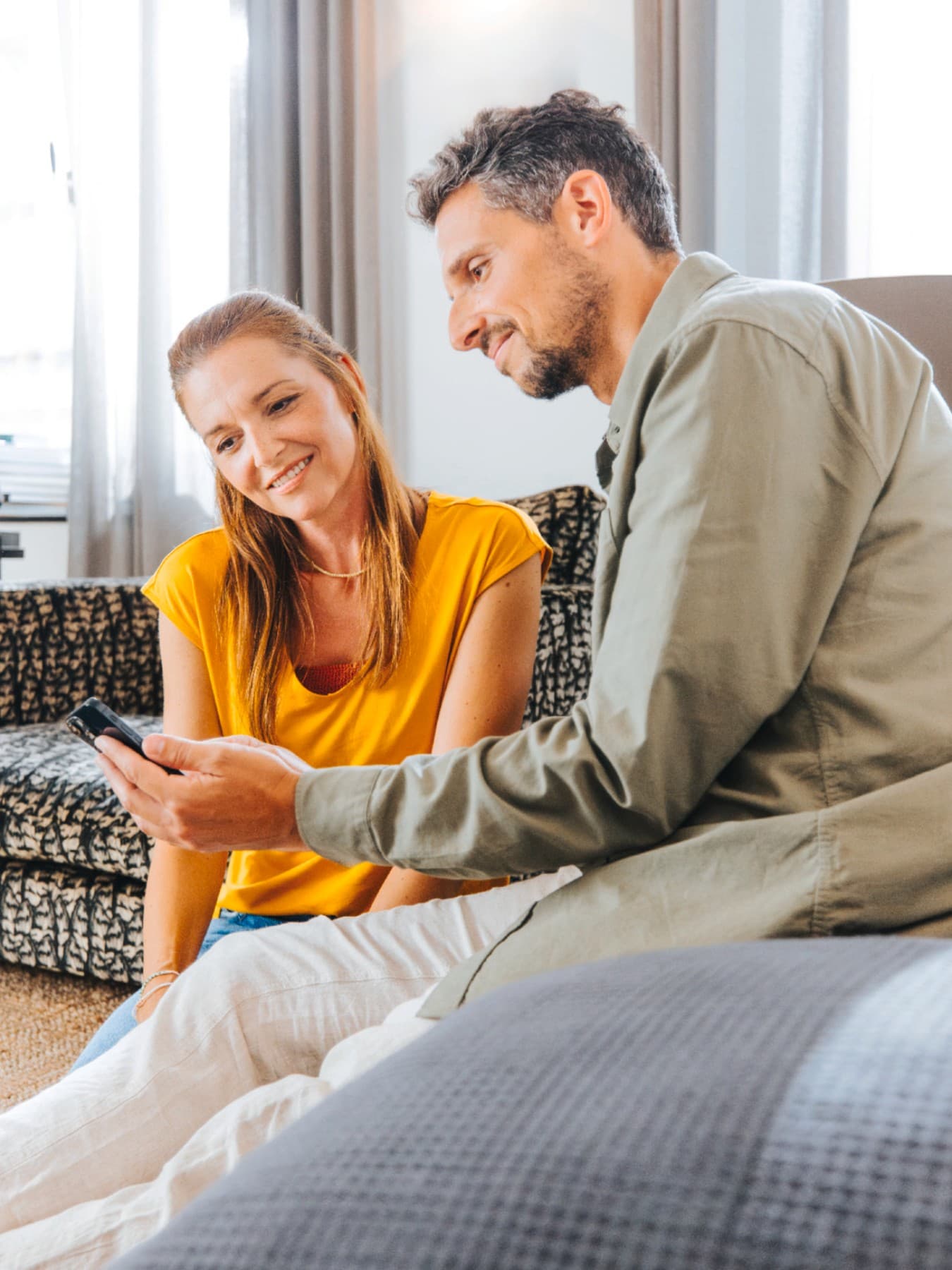 Un cuplu se uita pe smartphone in sufragerie