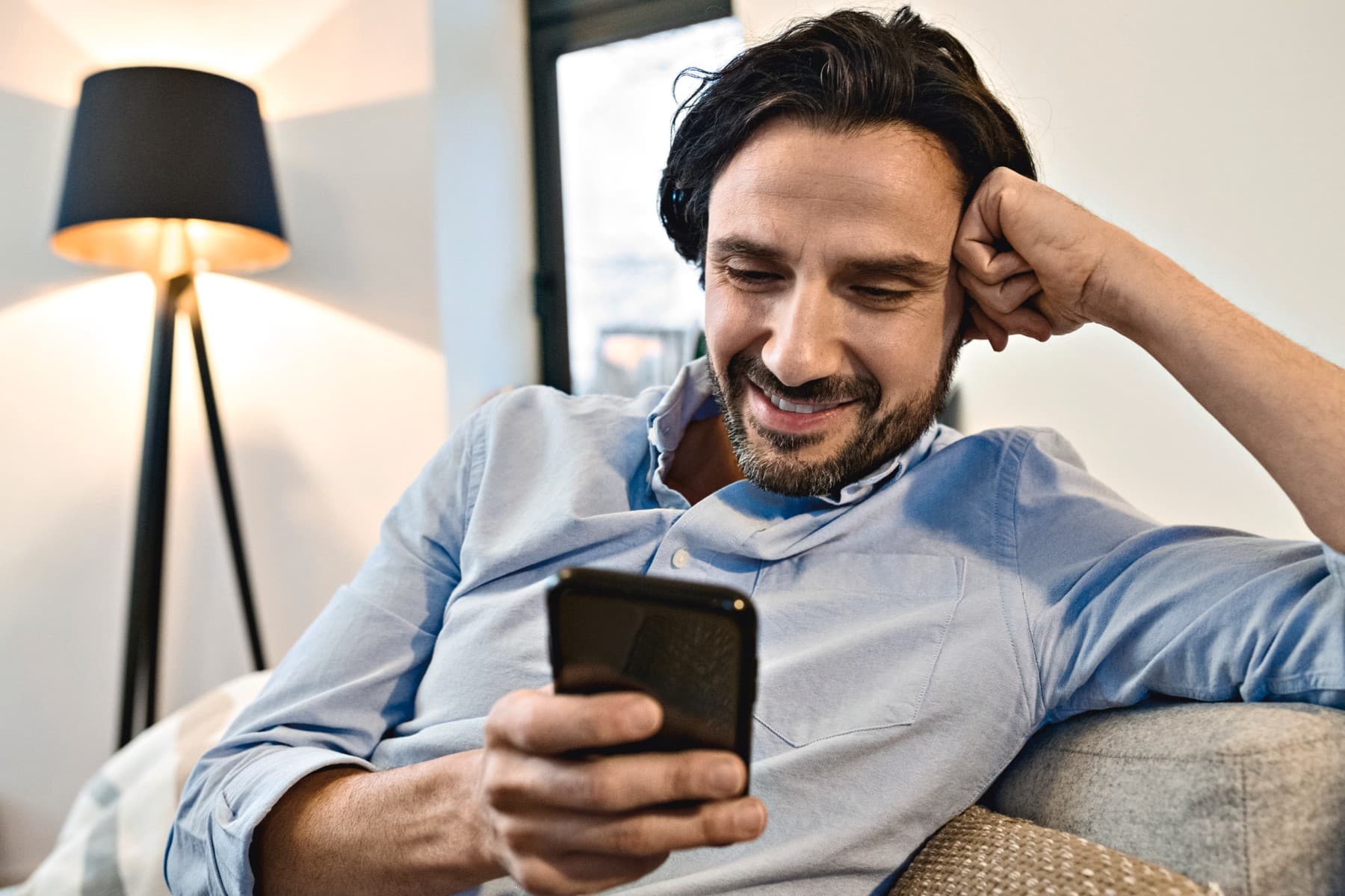 Un barbat care zambeste si se uita in telefon